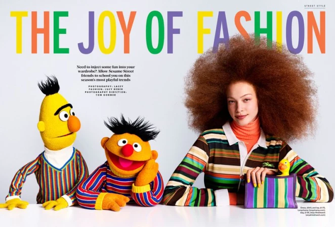 Tianna St. Louis poses with Bert and Ernie puppets wearing colorful striped sweaters against a white studio background.
