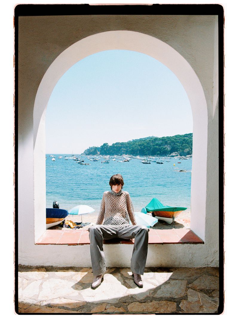 Estrella Gomez seated on an arch windowsill overlooking a Mediterranean coastal bay for Marie Claire Czech Republic.