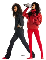 Two female models posing on a white backdrop, one wearing dark denim and the other in an all-red leather outfit with a camcorder.