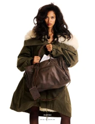 Model Jessie Aina holding a large brown leather Balenciaga bag while wearing an oversized olive parka with a shearling collar.