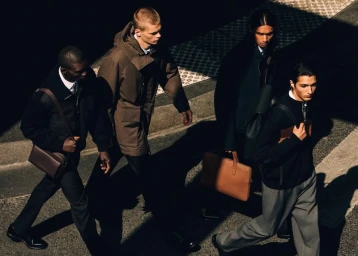 Four male models in tailored coats and designer bags walking across a sunlit street for Louis Vuitton Formal.