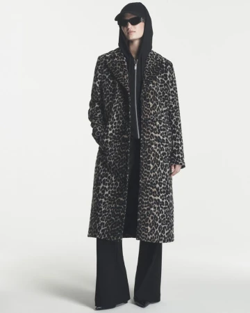 Model wearing a long leopard-print coat over a black hoodie and sunglasses against a white background.