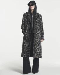 Model wearing a long leopard-print coat over a black hoodie and sunglasses against a white background.