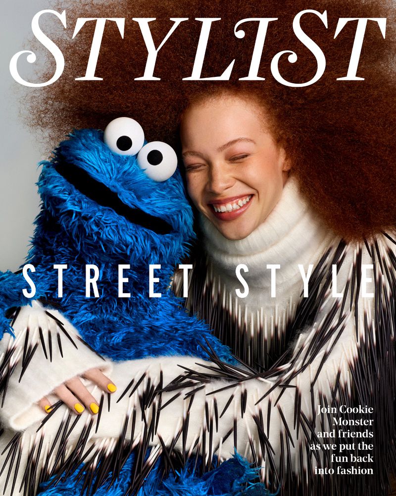 Model Tianna St. Louis with voluminous auburn hair smiling and embracing Cookie Monster on the cover of Stylist Magazine.