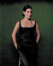 Sandra Bullock in a sleeveless black satin dress with a square neckline seated against a textured dark green studio backdrop.