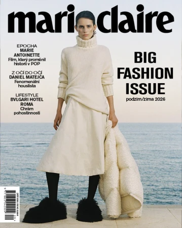 Model Estrella Gomez posing on a terrace in an ivory knit sweater, midi skirt, and fuzzy black shoes against the sea for Marie Claire.