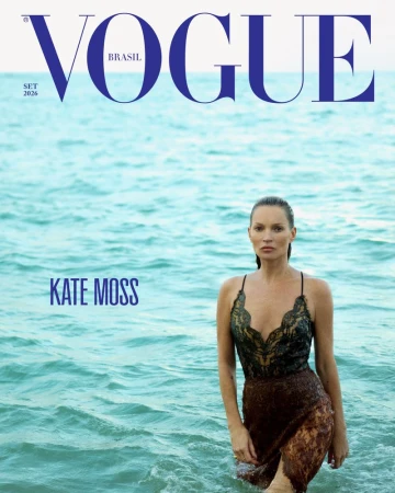 Kate Moss standing in turquoise ocean water wearing a dark lace slip dress on the cover of Vogue Brasil.