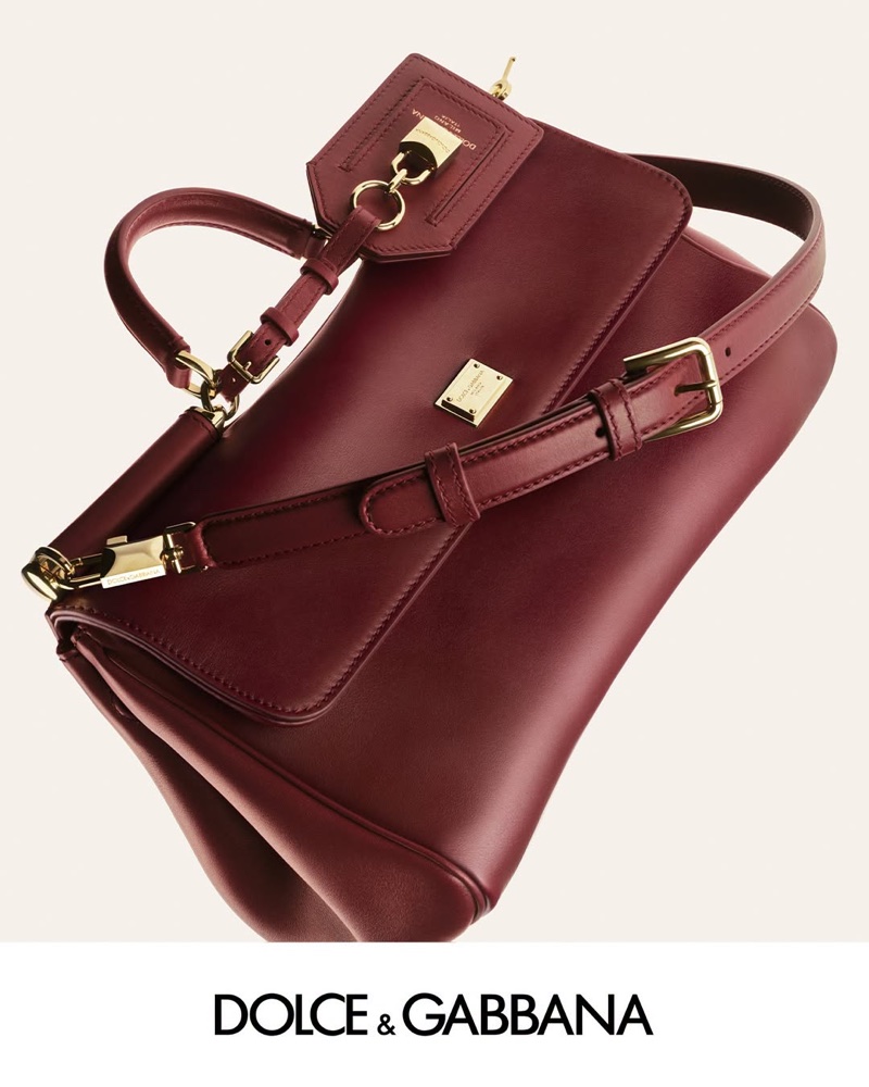 Burgundy leather Dolce & Gabbana handbag with gold hardware and shoulder strap against an off-white studio background.