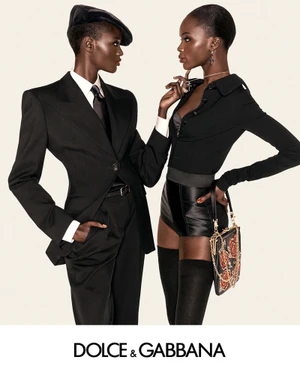 Two models in black Dolce and Gabbana autumn winter campaign apparel against a light seamless background.