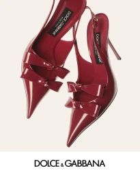 Two red patent leather slingback heels with double bows against a clean light background for Dolce and Gabbana