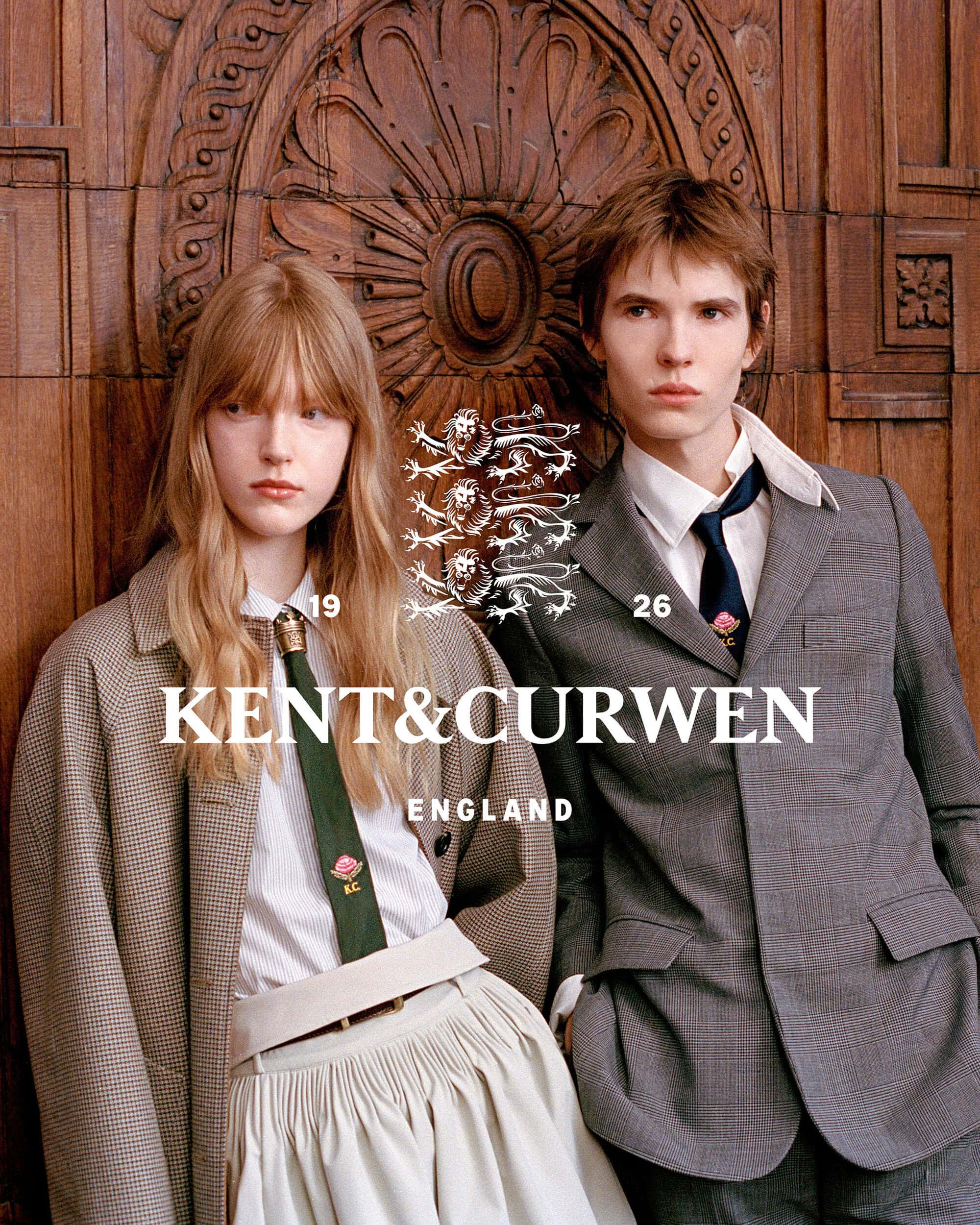 Two models wearing tailored suits and ties pose in front of an ornate carved wood panel for Kent & Curwen.