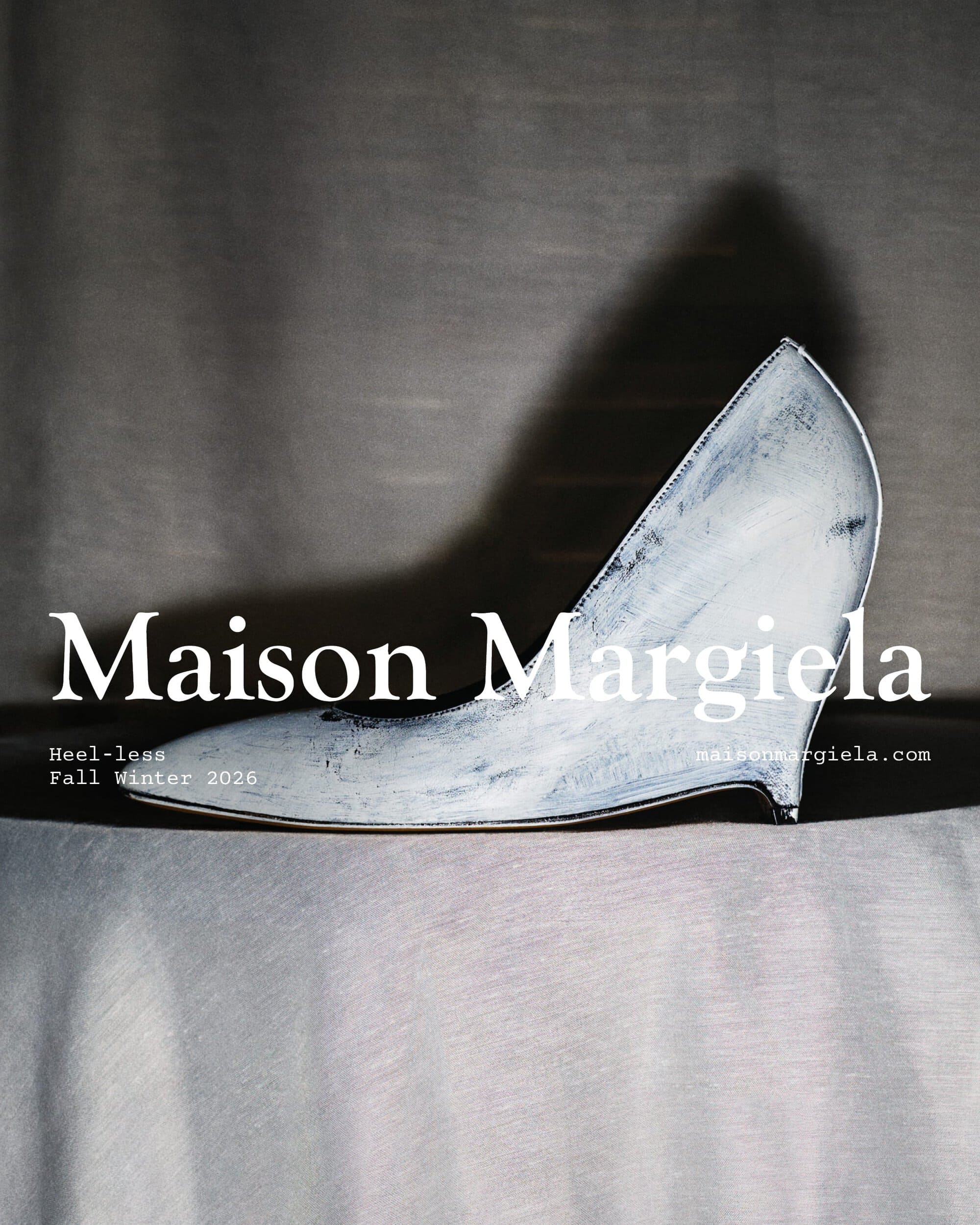 Distressed white heel-less high heel shoe displayed on a draped fabric surface for Maison Margiela.
