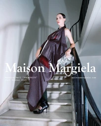Rebecca Hall in a draped fringed dress holding a silver handbag on a staircase for Maison Margiela Fall 2026 campaign.