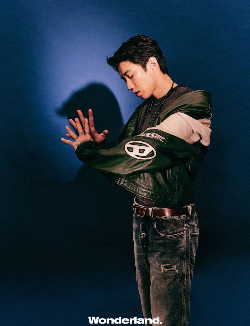 Jay Park posing in a dark green leather jacket and distressed denim jeans against a deep blue backdrop for Wonderland China.