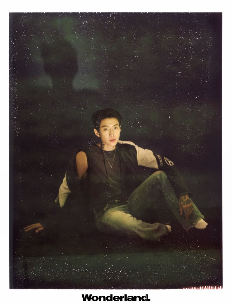 Musician Jay Park seated on the floor in a dark studio wearing a two-tone jacket, dark top, and denim jeans for Wonderland.