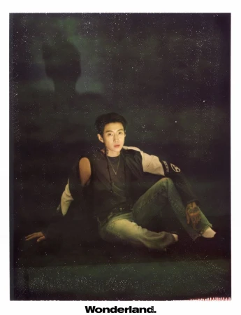 Musician Jay Park seated on the floor in a dark studio wearing a two-tone jacket, dark top, and denim jeans for Wonderland.