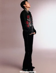 Jay Park standing in profile wearing an embroidered black shirt and black pants against a neutral studio backdrop.