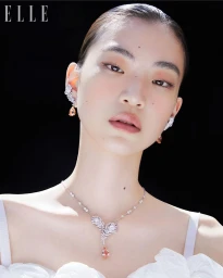 East Asian model wearing a Boucheron diamond and peach teardrop necklace and matching earrings against a black background.
