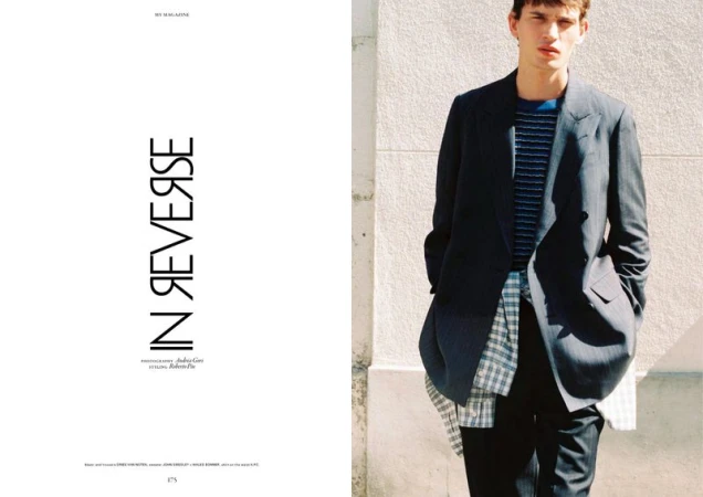 Magazine editorial spread titled In Reverse showing a male model in a dark blazer and layered plaid shirt against a sunlit wall.
