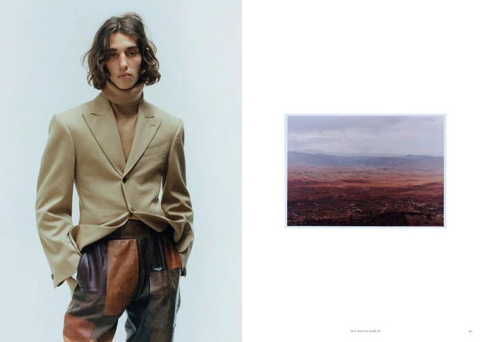 Model in a beige tailored blazer and patchwork leather trousers beside an inset landscape photo on an editorial magazine page.