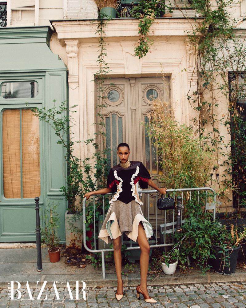 Model Muna Mahamed poses in a structured ruffled dress and heels by an ivy-clad Parisian doorway for Harper's Bazaar Arabia.