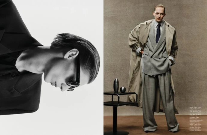 Fashion editorial with a gender-neutral model in a suit and trench coat standing next to a modern table with silver ornaments.