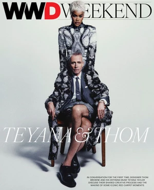 Teyana Taylor standing behind seated designer Thom Browne wearing a grey shorts suit and patterned coat in a studio.