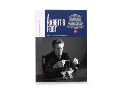 A Rabbit's Foot magazine cover issue 16 featuring actor Willem Dafoe in black and white holding paper figures on strings.