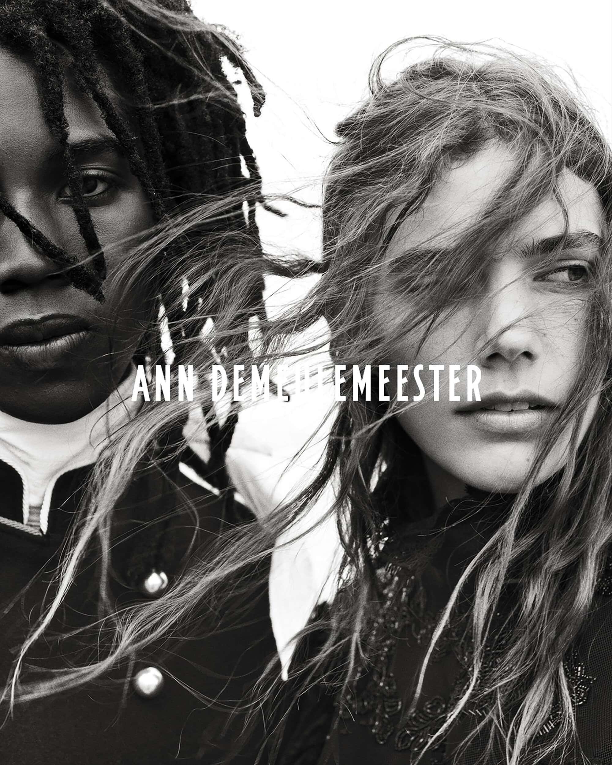 Monochrome close-up of two models with windswept hair wearing high-collared dark coats for Ann Demeulemeester.