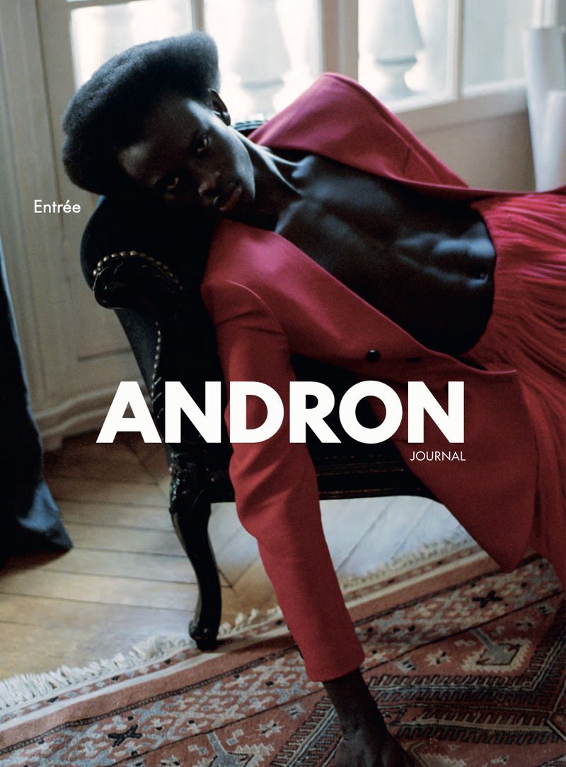 Magazine cover featuring a Black female model in a red blazer reclining on a black chair, set against a patterned rug and neutral backdrop.