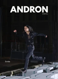 Model in a black shirt and trousers leaping across stacked concrete blocks at night outdoors