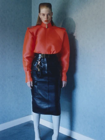 Model Vivian Jenna Wilson wearing an orange structured jacket and black leather skirt for Mugler Fall 2026.