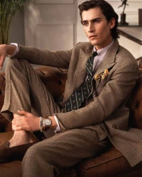 Man wearing a brown plaid suit and striped tie seated on a leather sofa for a Polo Ralph Lauren campaign.