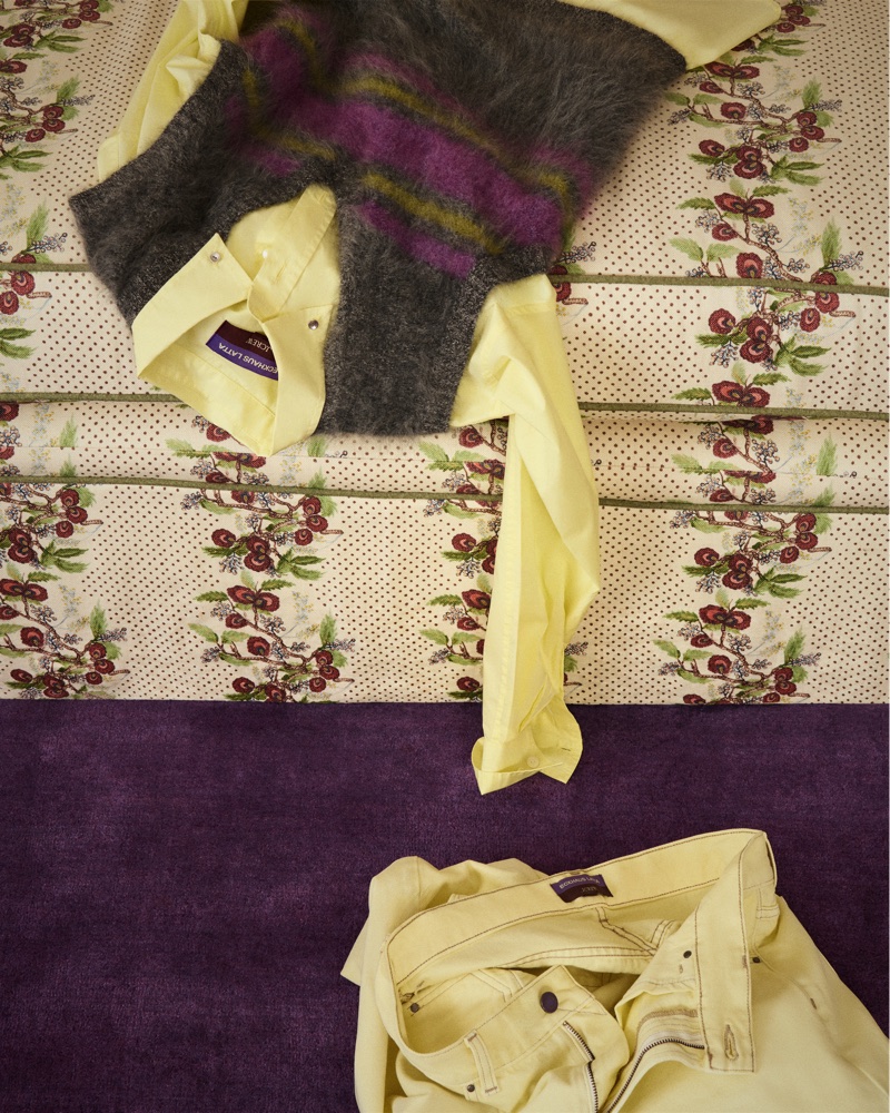 Folded yellow shirt and striped mohair vest resting on a patterned upholstered surface with matching yellow trousers below.