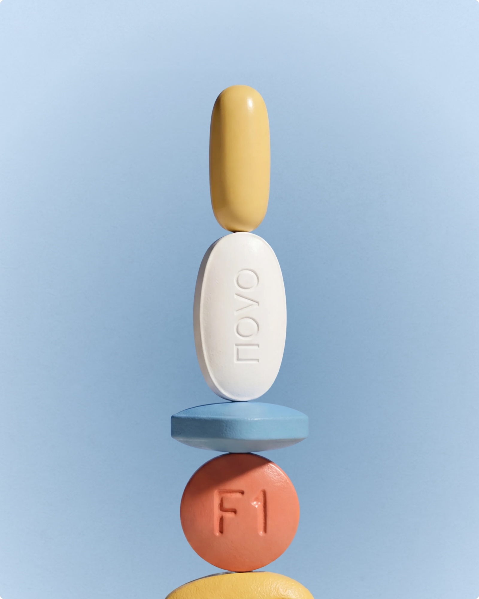 A balanced vertical stack of assorted colorful pills, tablets, and capsules aligned against a light blue background.