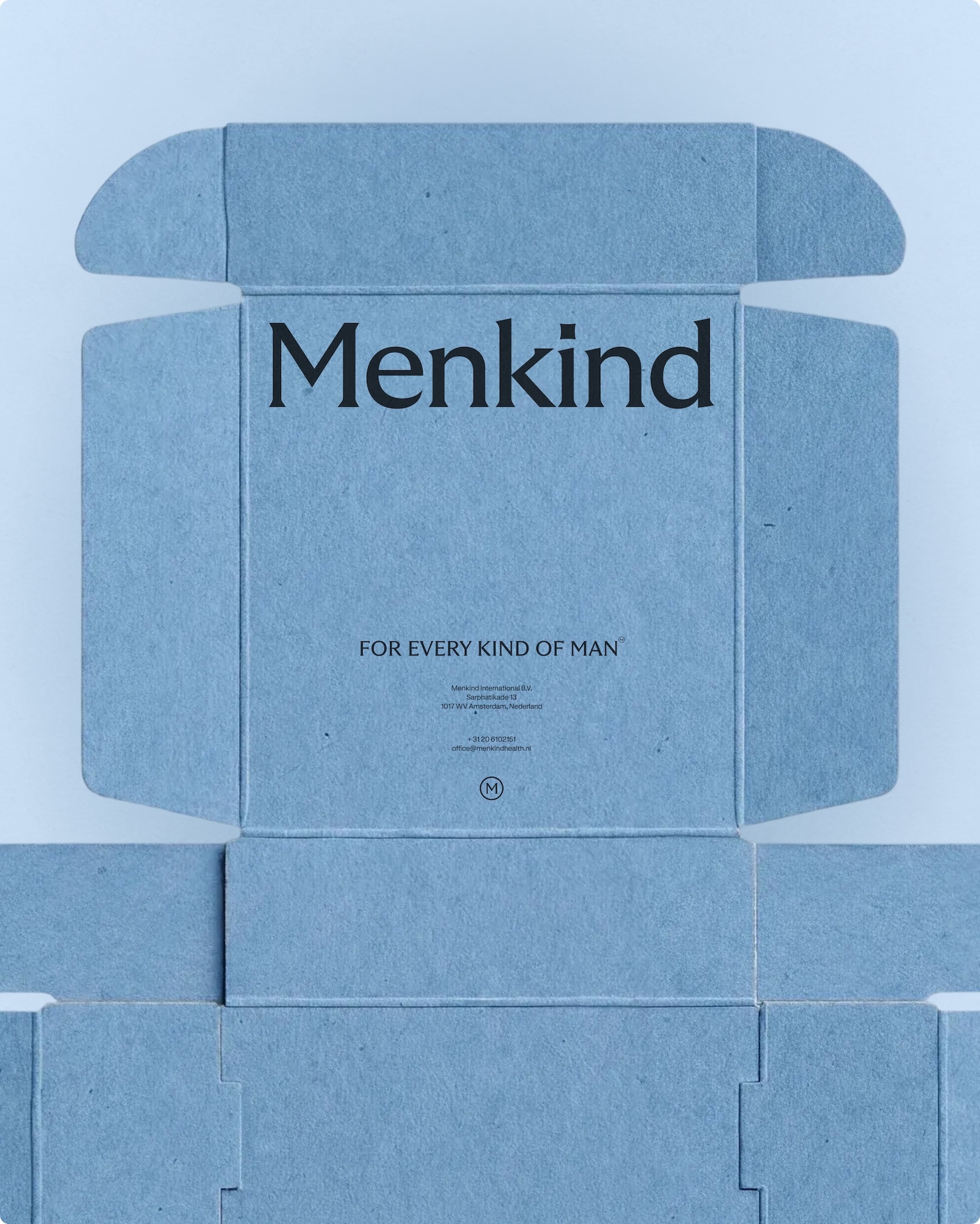 Unfolded light blue textured cardboard packaging box with printed Menkind branding against a pale background.