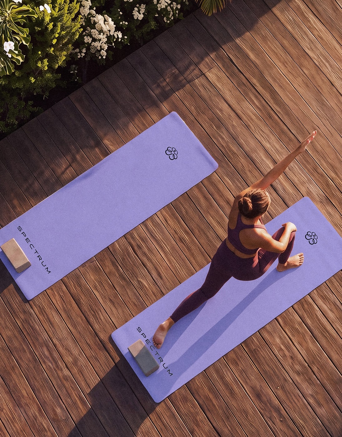 High-angle view of a woman in plum activewear stretching on a lavender yoga mat on a sunlit wooden deck.