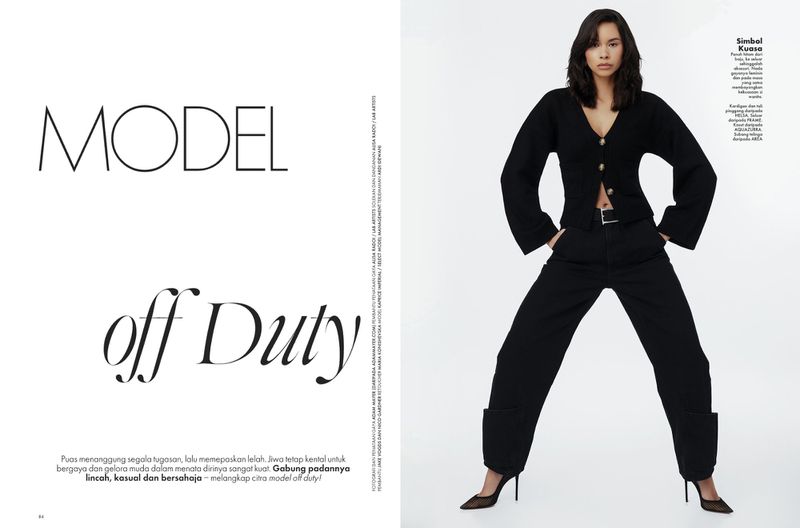 A full-length shot of a woman in a black cardigan and trousers, posing against a white background, featured in an editorial fashion spread.