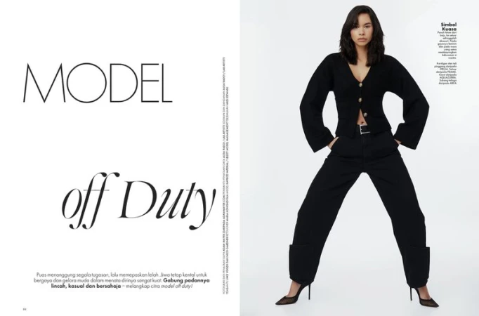 A full-length shot of a woman in a black cardigan and trousers, posing against a white background, featured in an editorial fashion spread.
