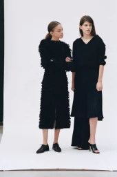 Two female models in black textured outfits posing against a plain white background for Beyond Noise.