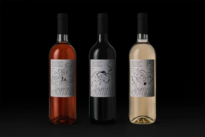 Three wine bottles with illustrated labels standing upright against a dark black studio background