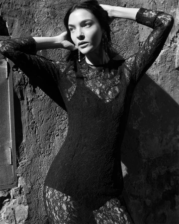 Mariacarla Boscono in a black lace dress posing against a textured wall for Dolce & Gabbana DNA campaign