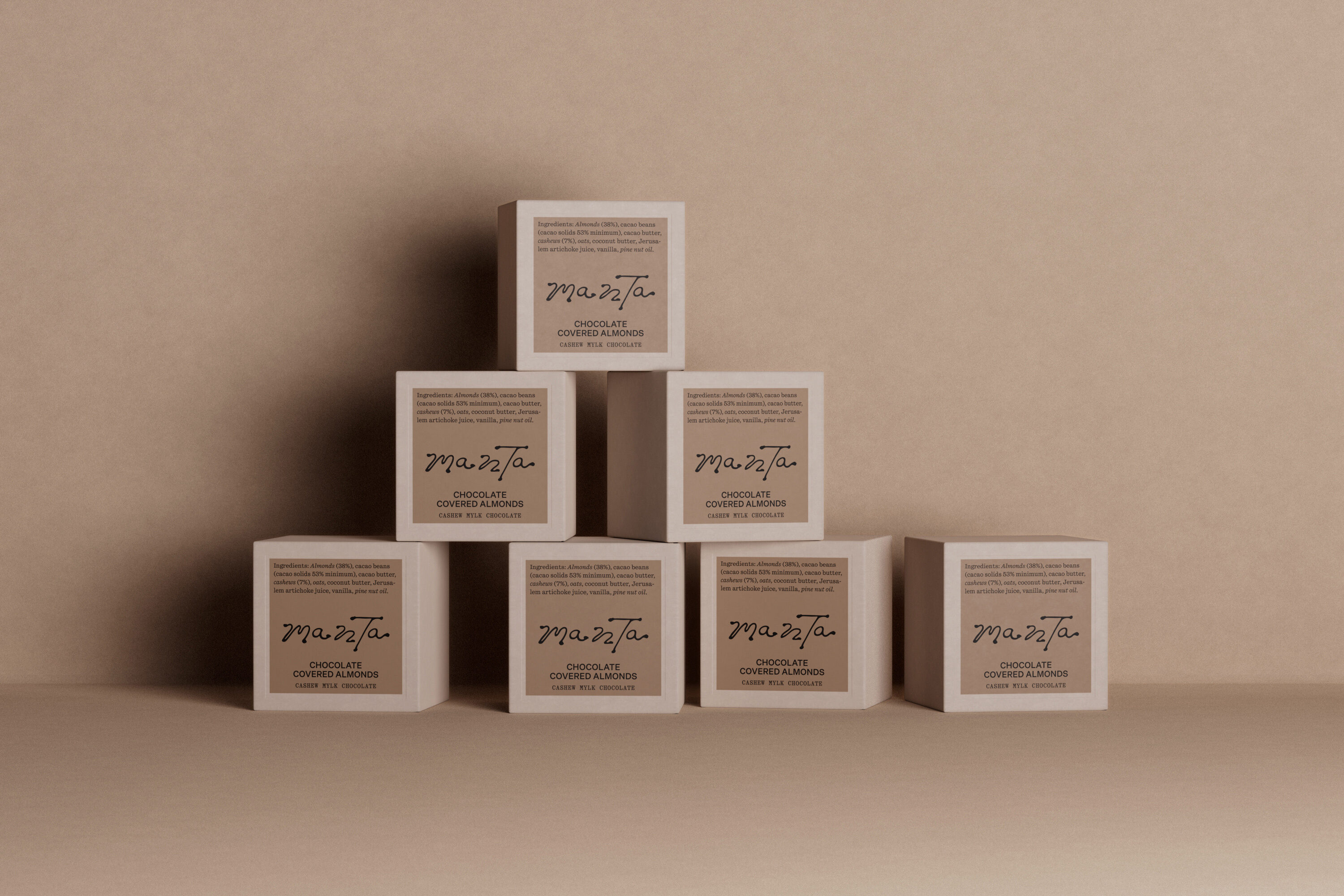 Stacked square Manta chocolate packaging boxes against a neutral beige background