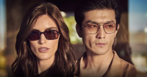 Close-up portrait of a woman and a man wearing designer sunglasses outdoors in soft warm light for Oliver Peoples.