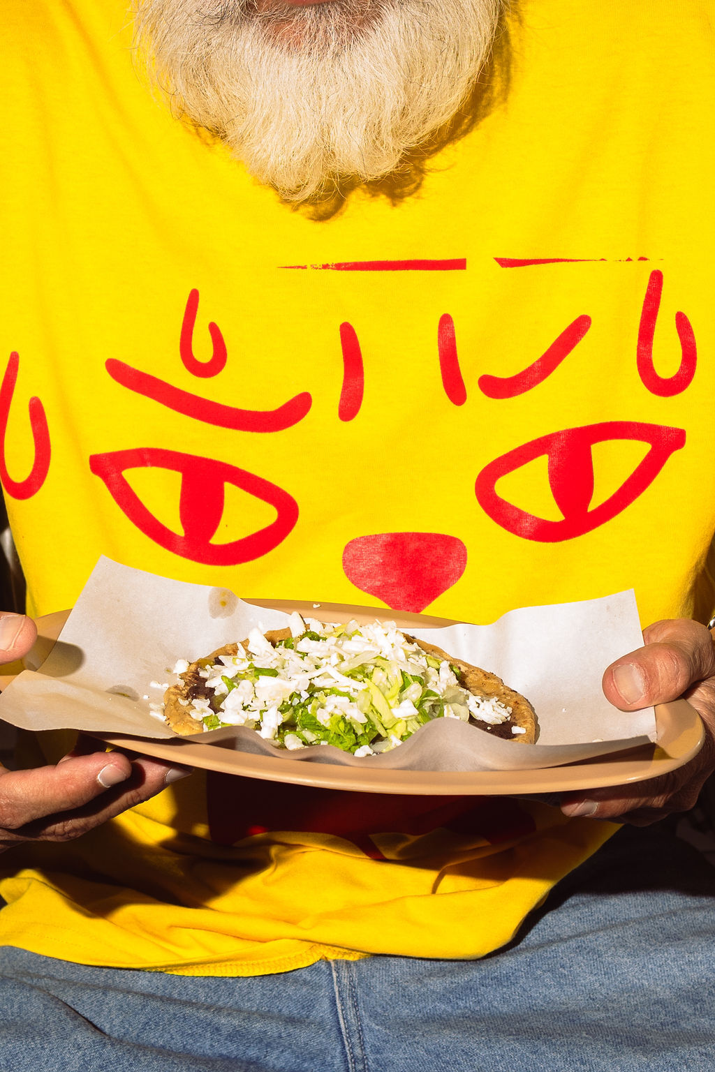 Man wearing a yellow graphic t-shirt holding a tray with a taco for Salsa Mutua brand identity