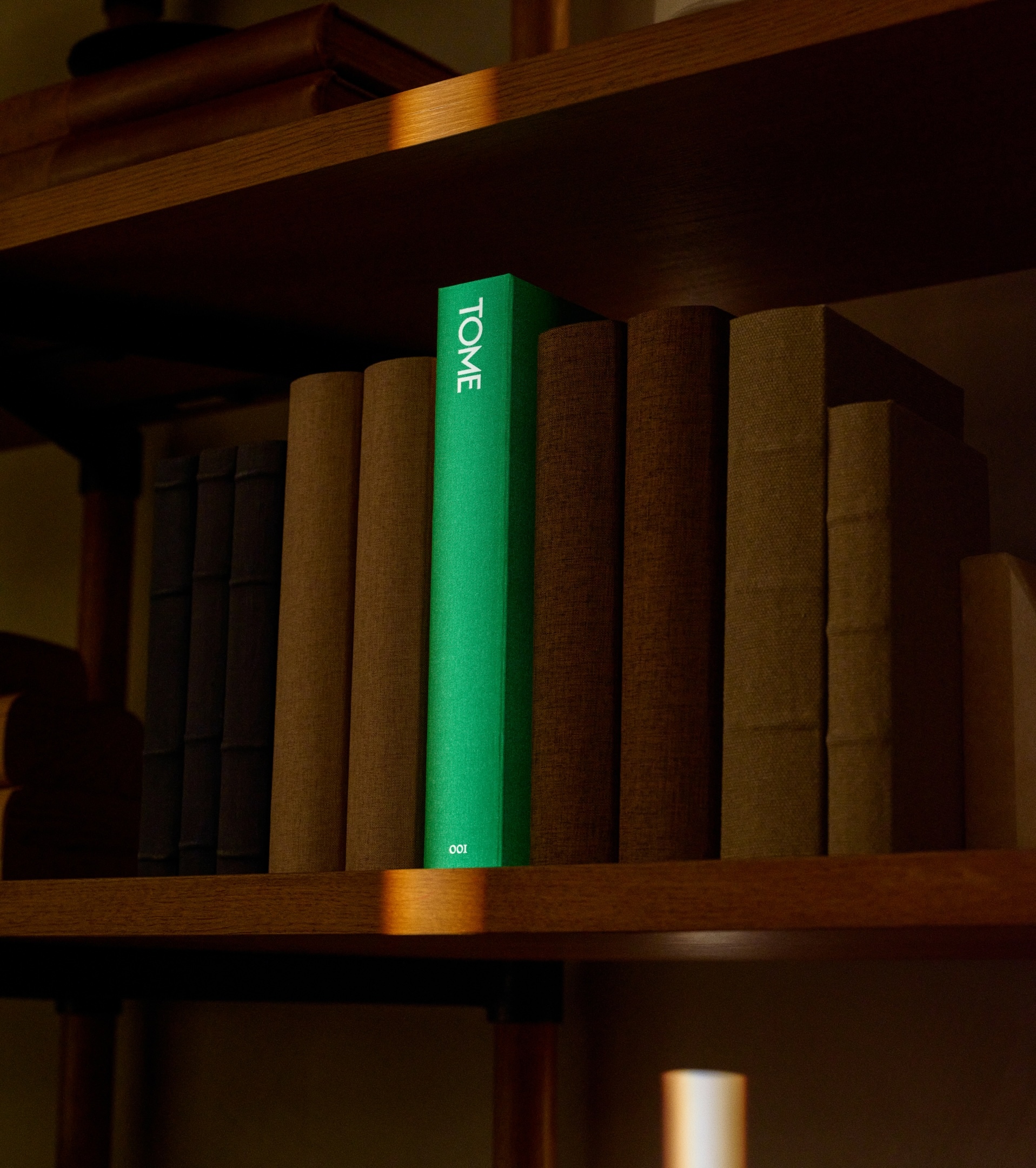 Bright green Tome branded book standing vertically between brown books on a wooden bookshelf