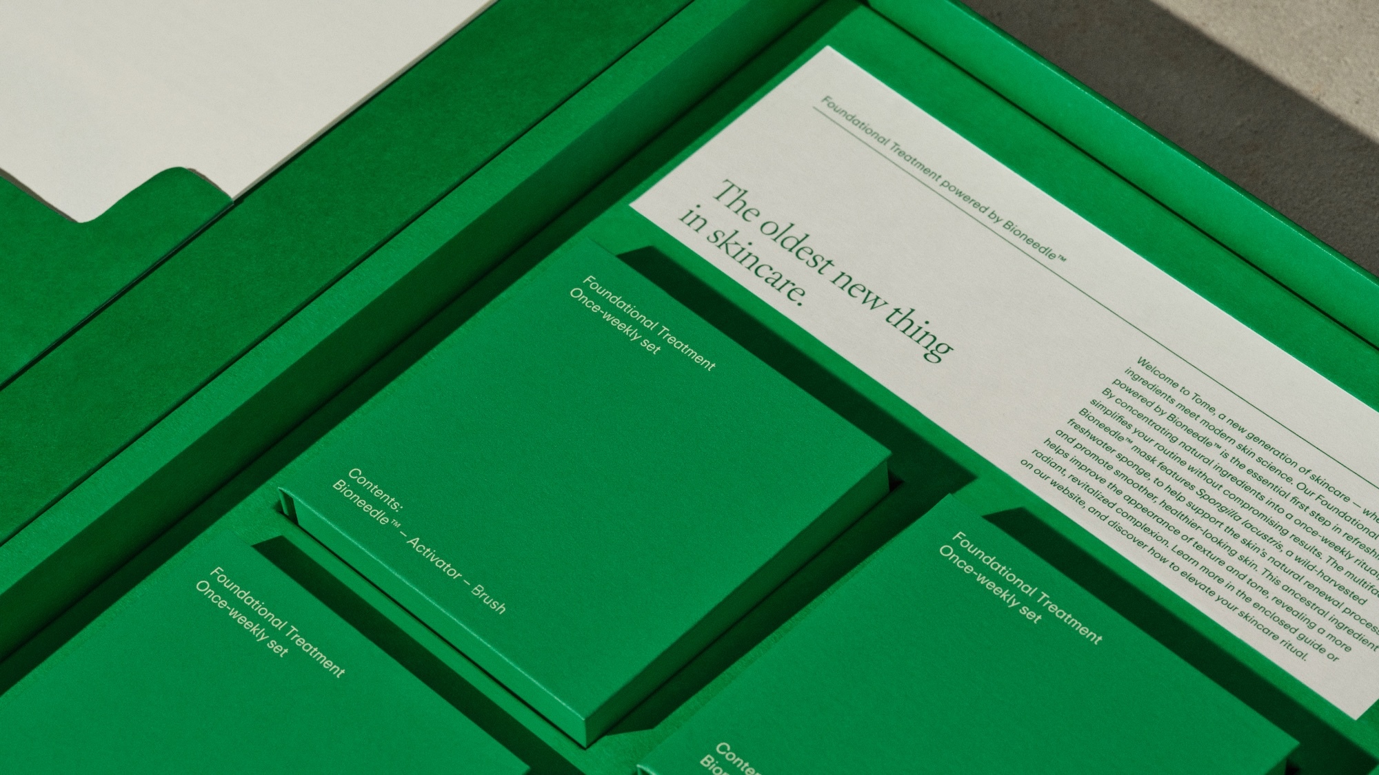 Green presentation box for Tome skincare containing custom compartments, text cards, and product packaging items.