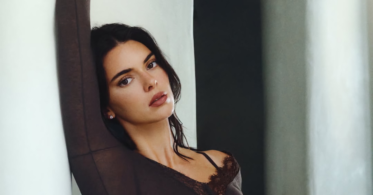 Kendall Jenner posing against a light wall for Intimissimi wearing a dark top