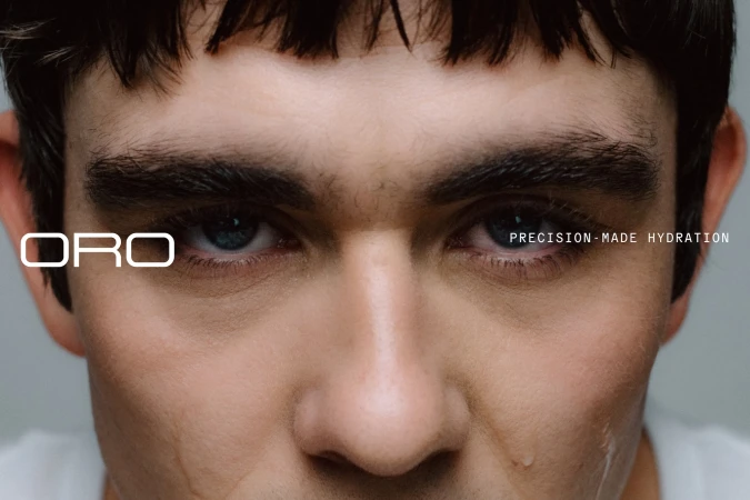Close-up portrait of a young man's face with dark hair and intense gaze, featuring minimalist white typography for Oro brand identity.