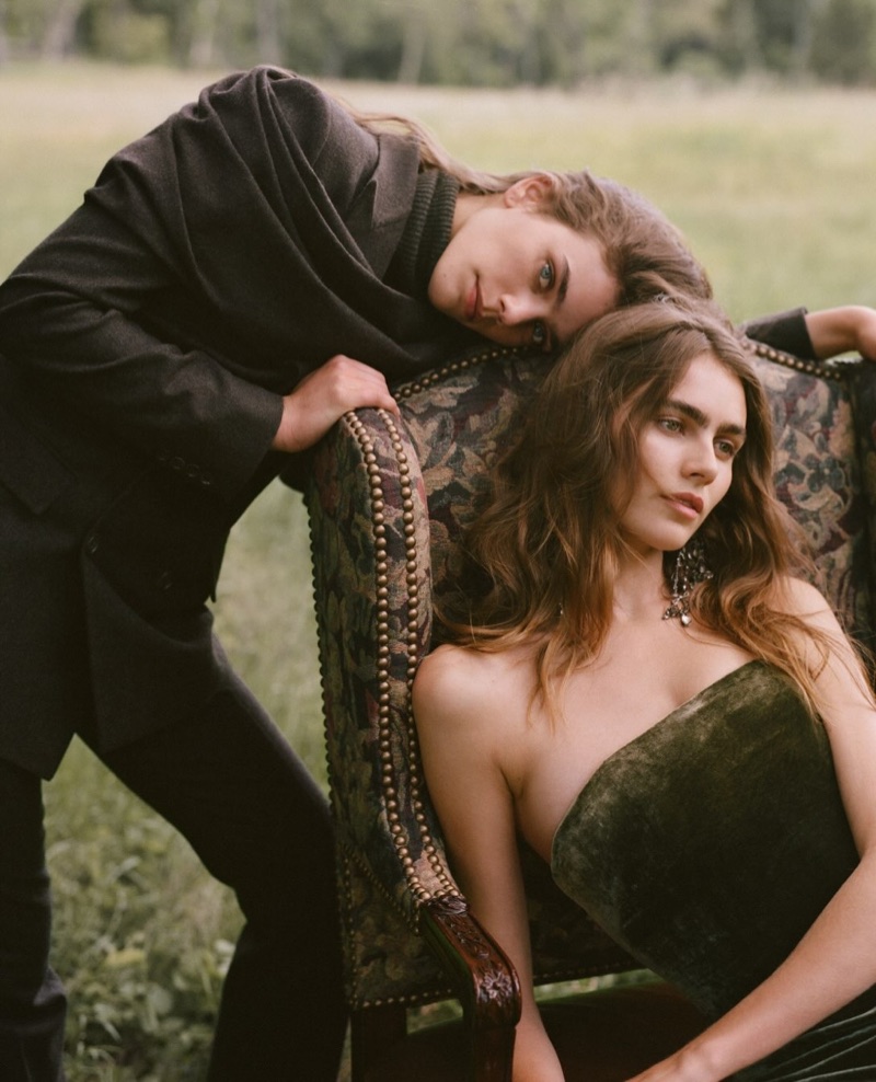 Two women posing outdoors with an antique upholstered armchair in a grassy field for the Ralph Lauren Fall 2026 Collection
